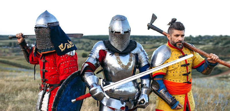 Medieval knights with swords and axe poses in armour, great fighter. Armored ancient warriors in armor posing in the field